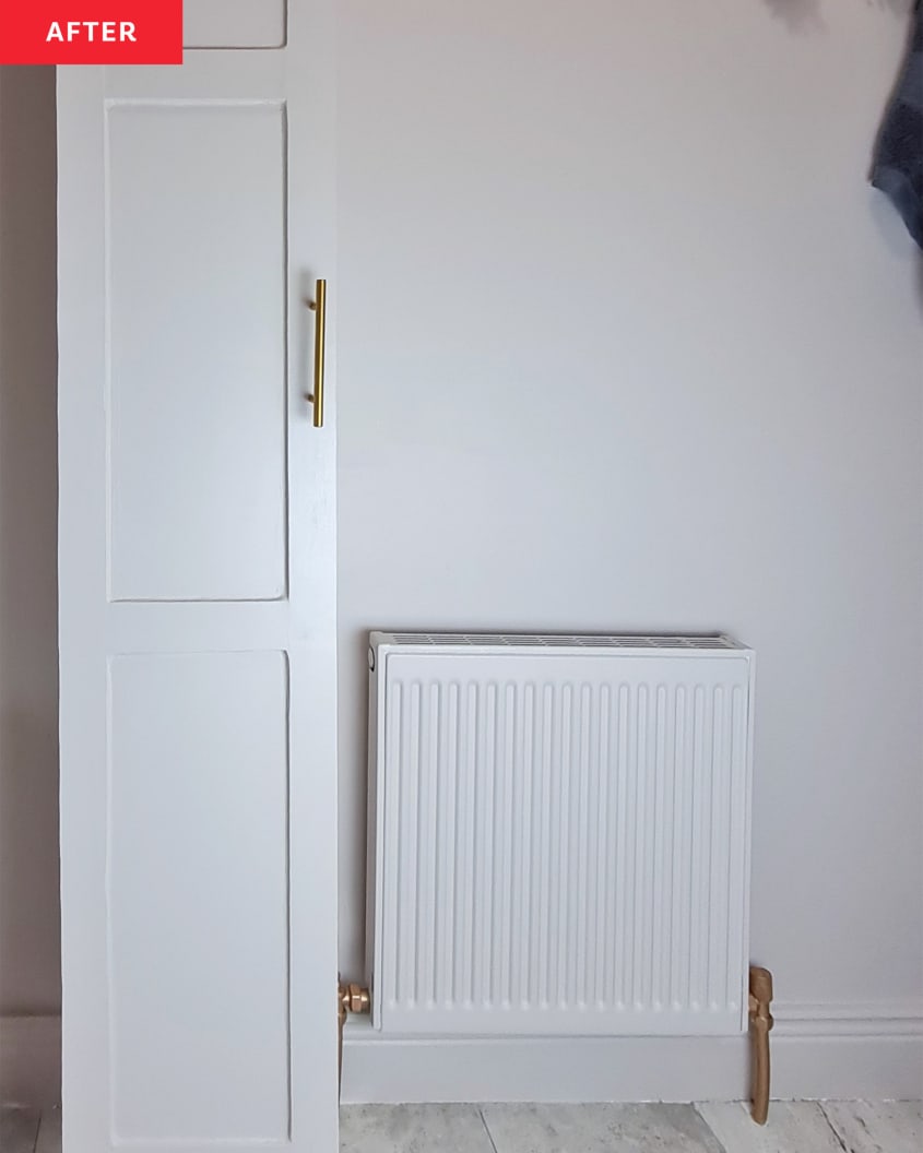 White cabinet and heater with golden brass hardware in a white bathroom.