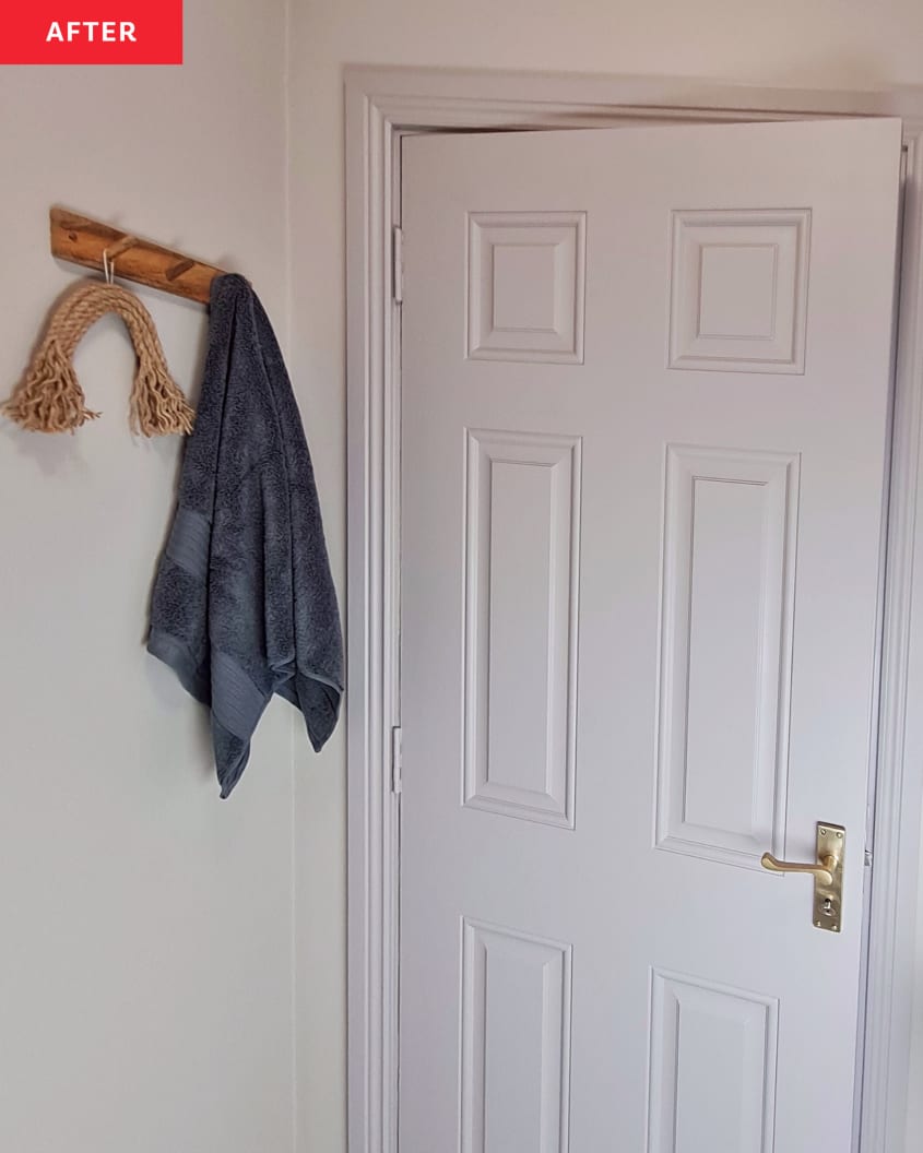 A wooden clothing hook in white bathroom, near white door.