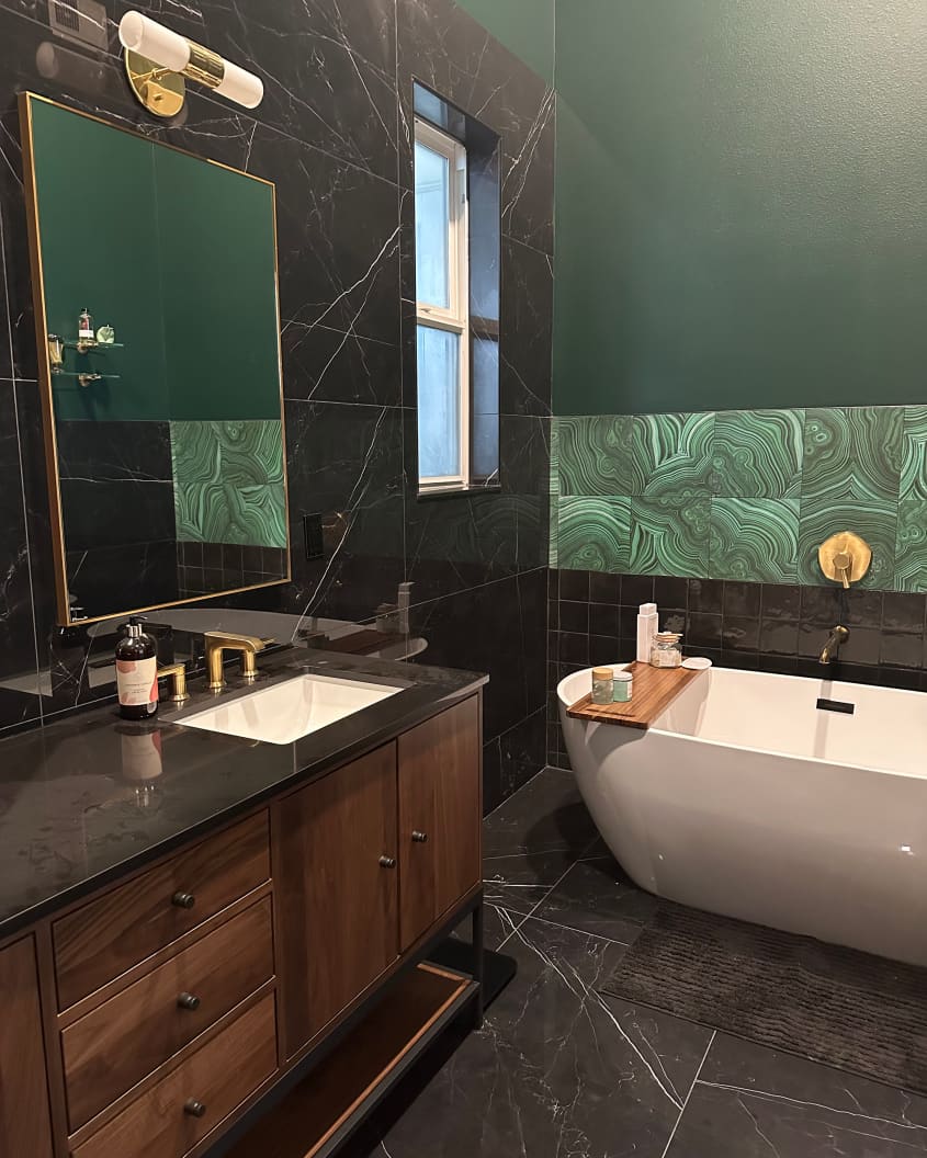 Vanity and soaking tub in green and black tiled bathroom after renovation.