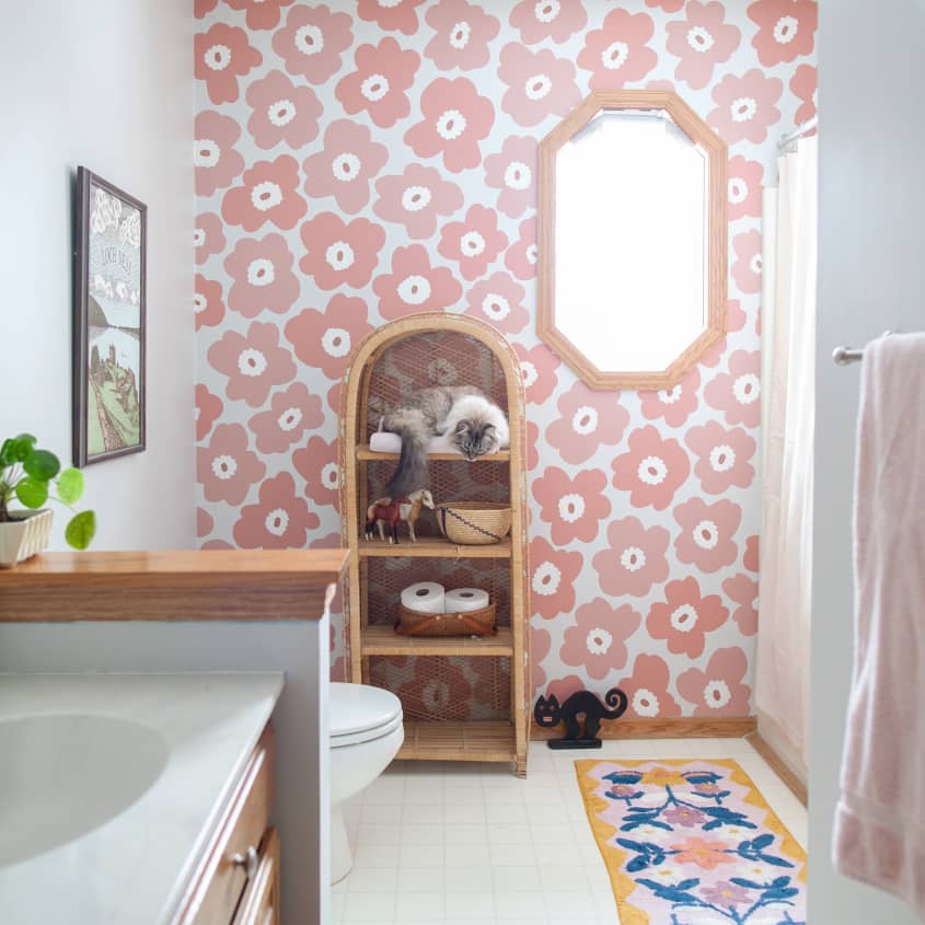Bathroom with pink floral wallpaper and arch-shaped wicker shelf