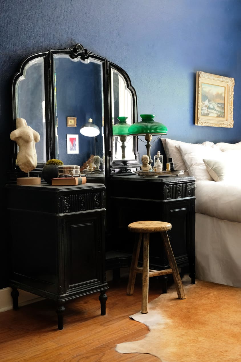 Black antique vanity next to bed in room with blue walls