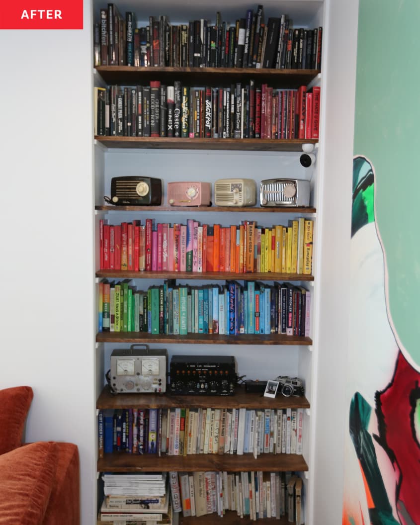 Color coded books arranged on built in bookshelf in living room of renovated home. Various vintage radios line one shelf.