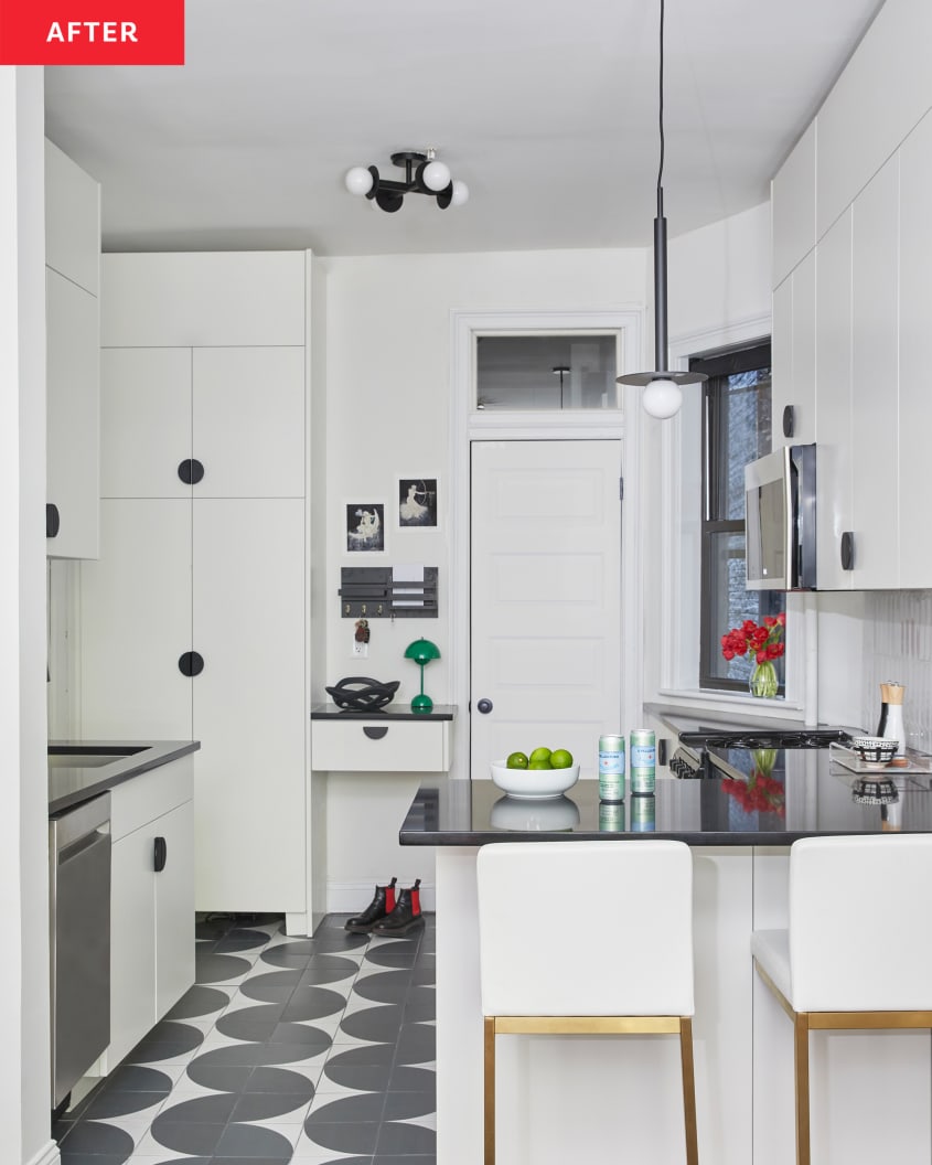 Black and white tiles line newly renovated kitchen with white cabinets and black hardware.