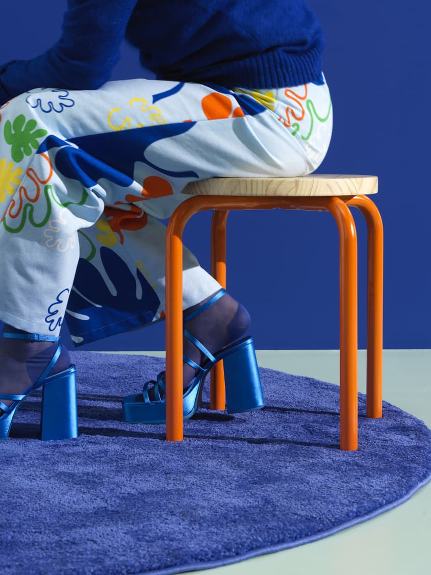 Colorful studio photo of items from the IKEA 80th anniversary Nytillverkad collection - stool with orange legs and printed pajamas