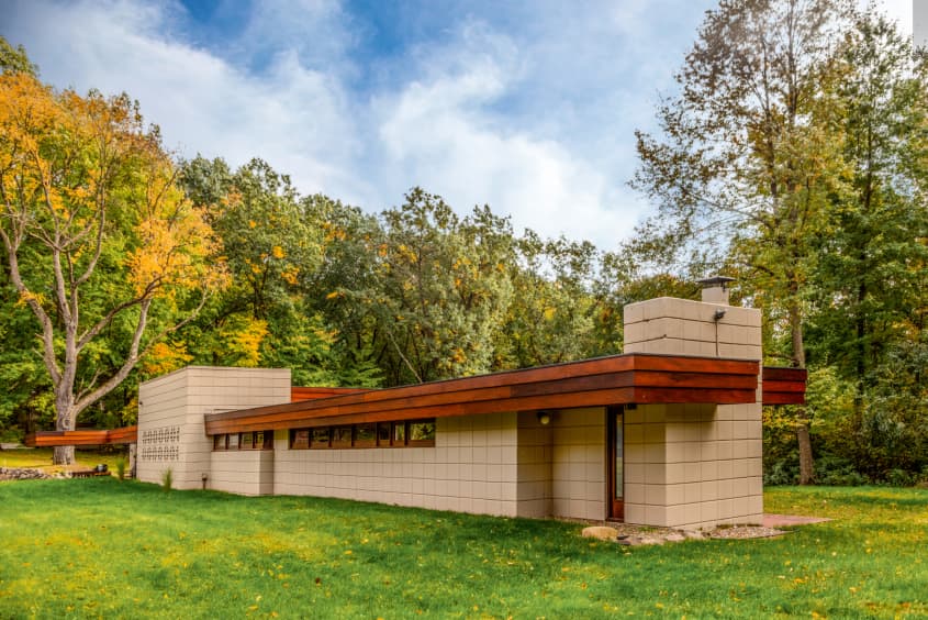 exterior of a mid century modern angles home long, slender, flat roof with off white cement tile