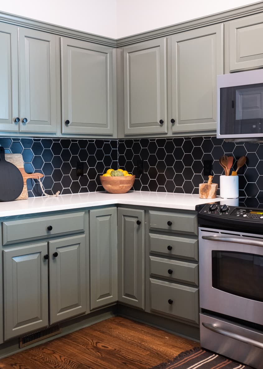 Kitchen with sage green cabinetry and a matte black hexagonal backsplash and stainless steel appliances designed by Marie Cloud of Indigo Pruitt