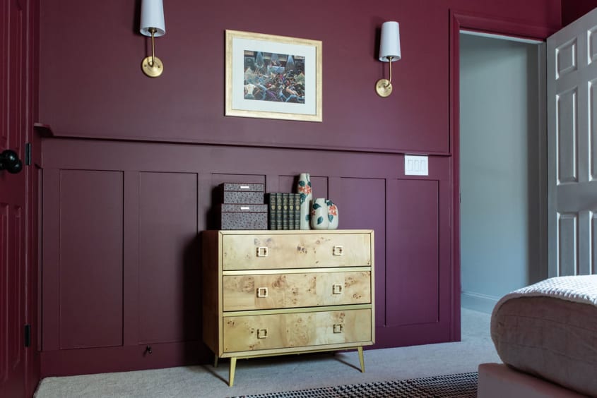 Beautiful moody burgundy bedroom with a burl wood desser