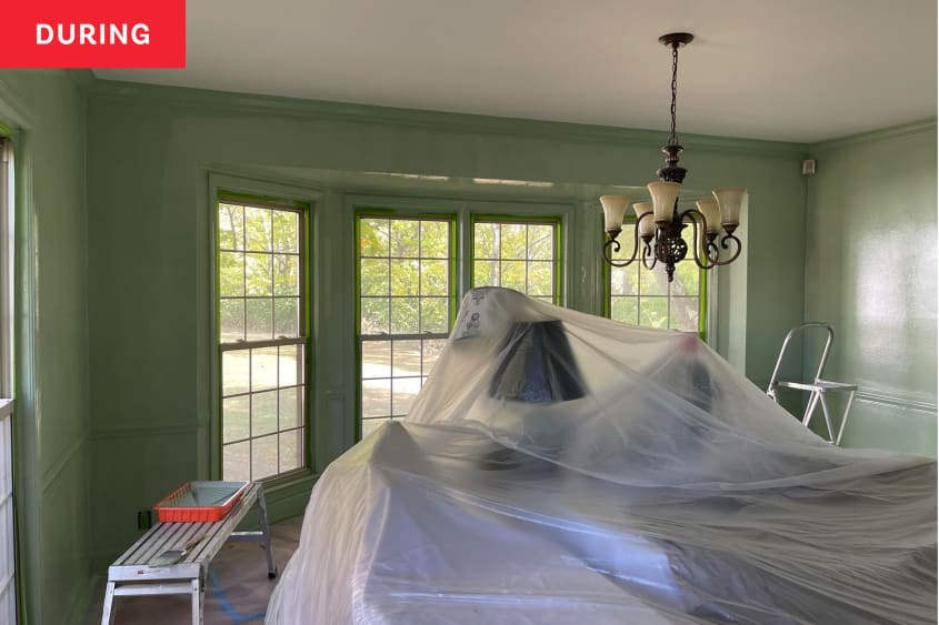 Photo of room during transformation into home office: furniture is covered by a plastic tarp and new green paint color has been applied