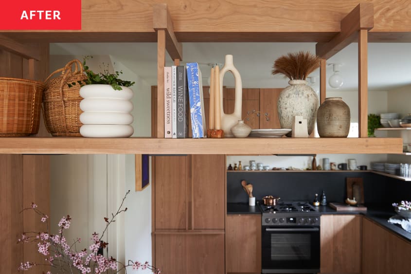 Walnut colored open kitchen shelves displaying vases, cookbooks and other decorative objects.