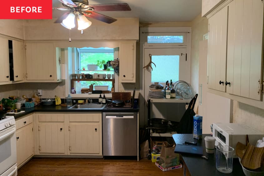 Kitchen with dim overhead lighting and cream colored cabinets before renovation.