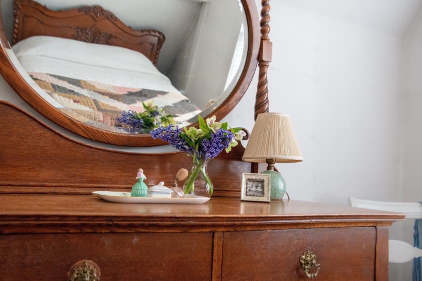 Reflection of antique bed in mirror of antique dresser