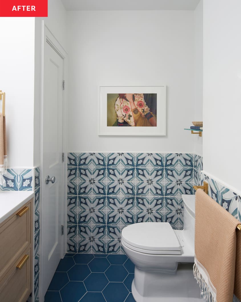 Colorful art print mounted on white wall in blue and white newly renovated bathroom.