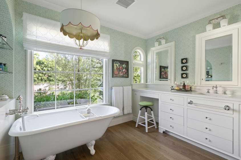 green and white bathroom with wood floor and claw foot tub