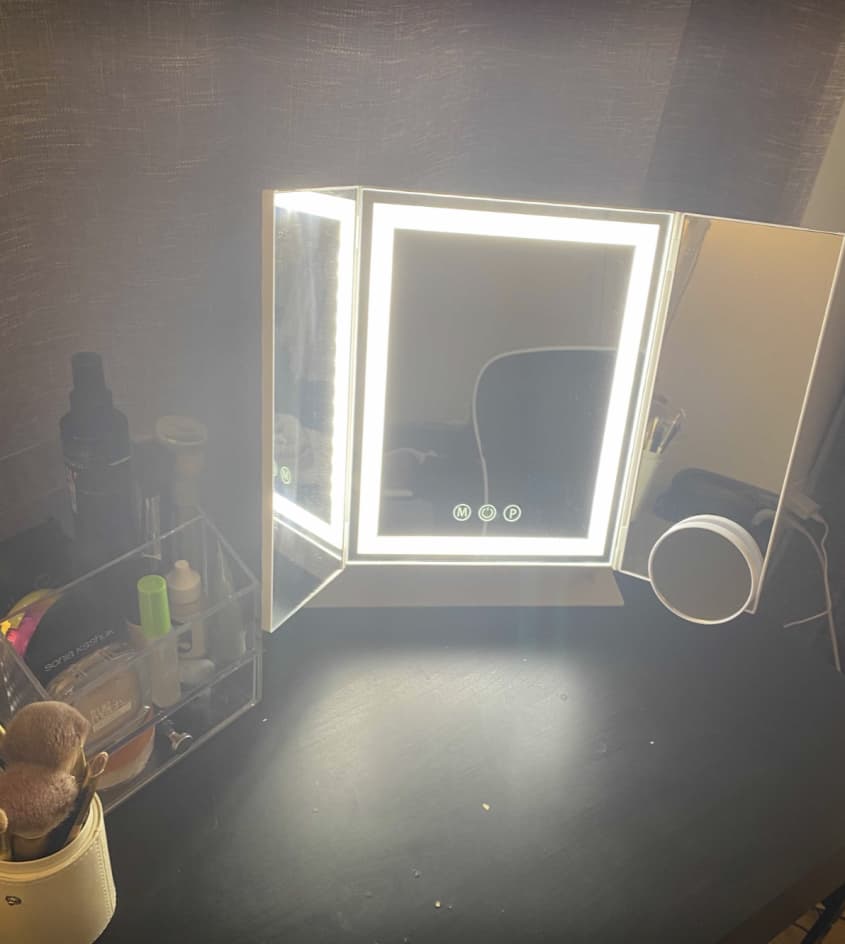 white trifold mirror lit up on desk with makeup products