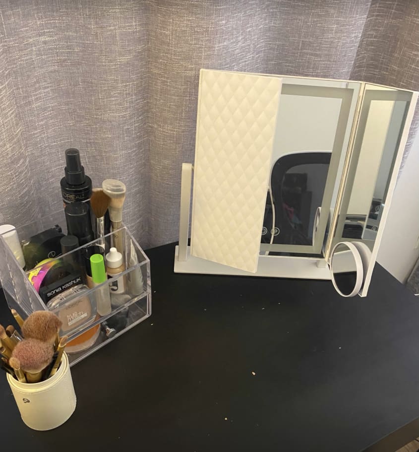 white trifold mirror on desk with makeup products