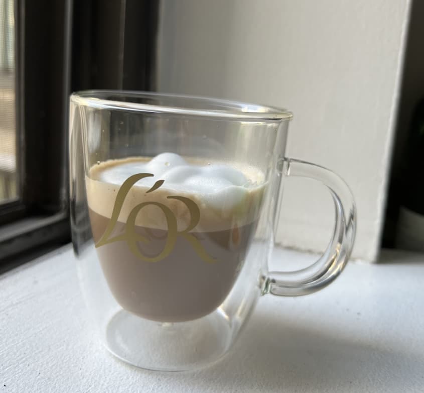 a cup of coffee in a L'OR brand glass mug