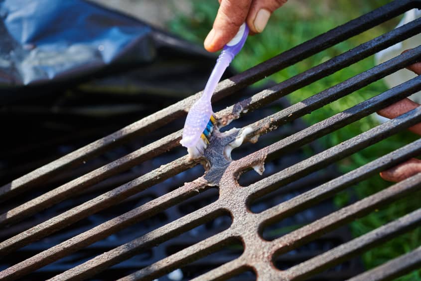 Scrubbing grill grate with toothbrush and baking soda mixture