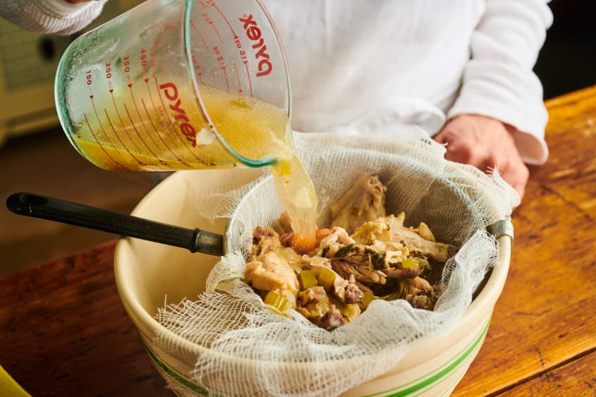 straining chicken stock into a large bowl with cheesecloth