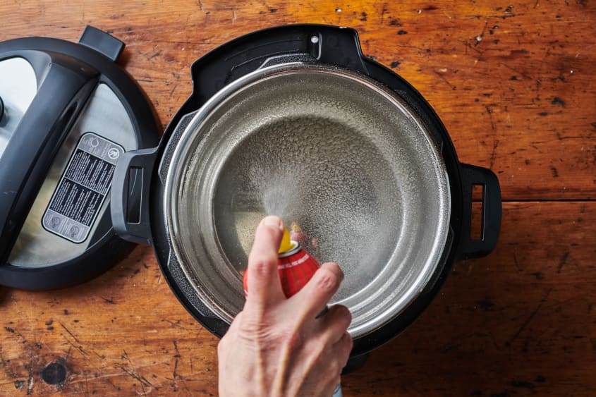 Cooking spray is sprayed into the bowl of the instant pot.