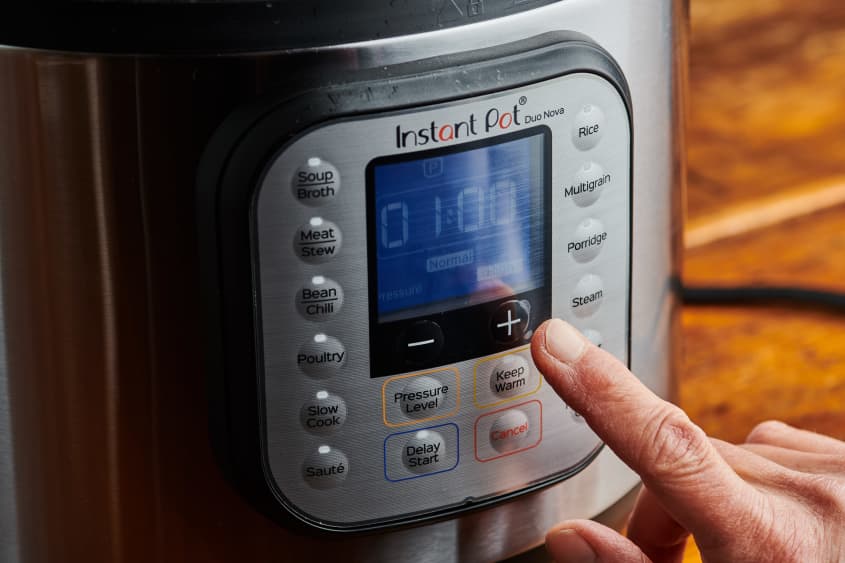 A finger turns the instant pot on.
