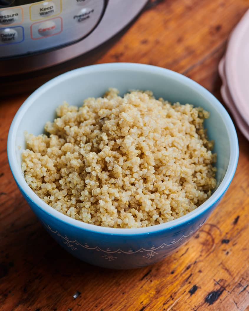 A bowl of fluffy quinoa sits in front of an instant pot.