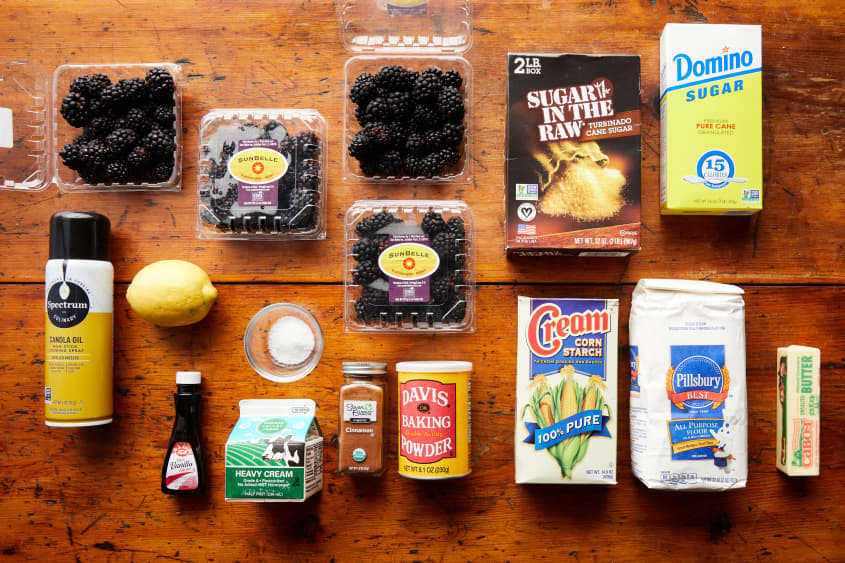 all ingredients laid out on kitchen counter: (1) whole lemon, (1) bag/box of sugar (3) pints of blackberries (1) container cornstarch (1) bottle vanilla extract (1) bottle of cinnamon (1) bag of flour (1) container baking powder (1) box of salt or pinch in bowl (1) stick of butter (1) carton heavy cream (1) box of turbinado sugar/ sugar in the raw