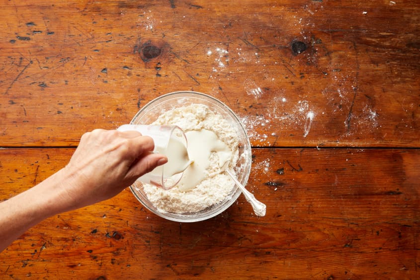 Buttermilk is added to the glass bowl filled with dry ingredients.