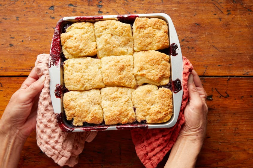With two taels, hands hold the baked berry cobbler.
