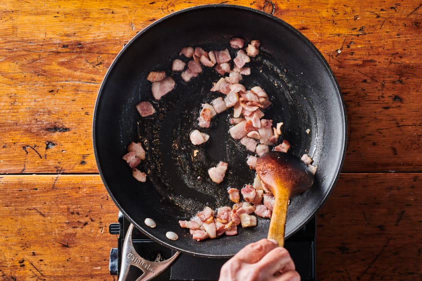 diced bacon being stirred in skillet