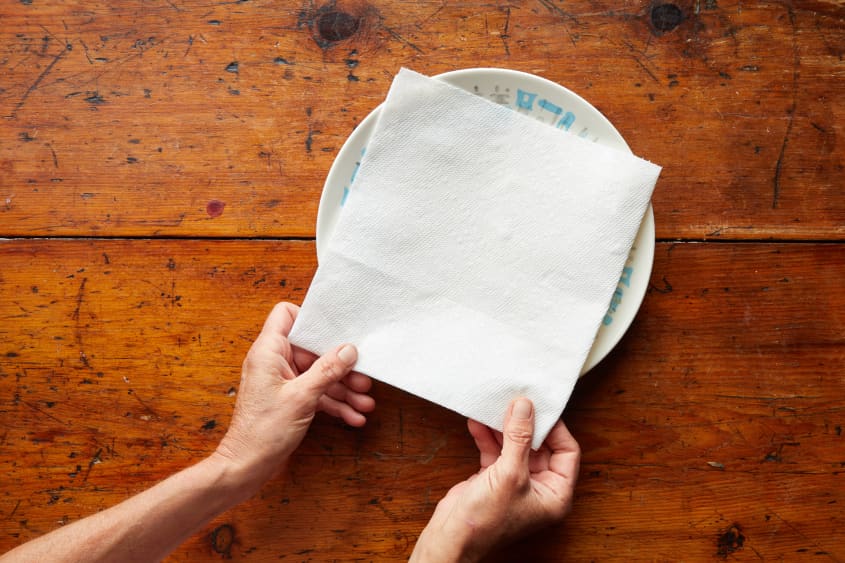 Someone placing paper towel on plate.
