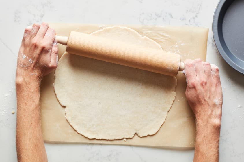 The pie dough is rolled out with a wooden pastry roller.