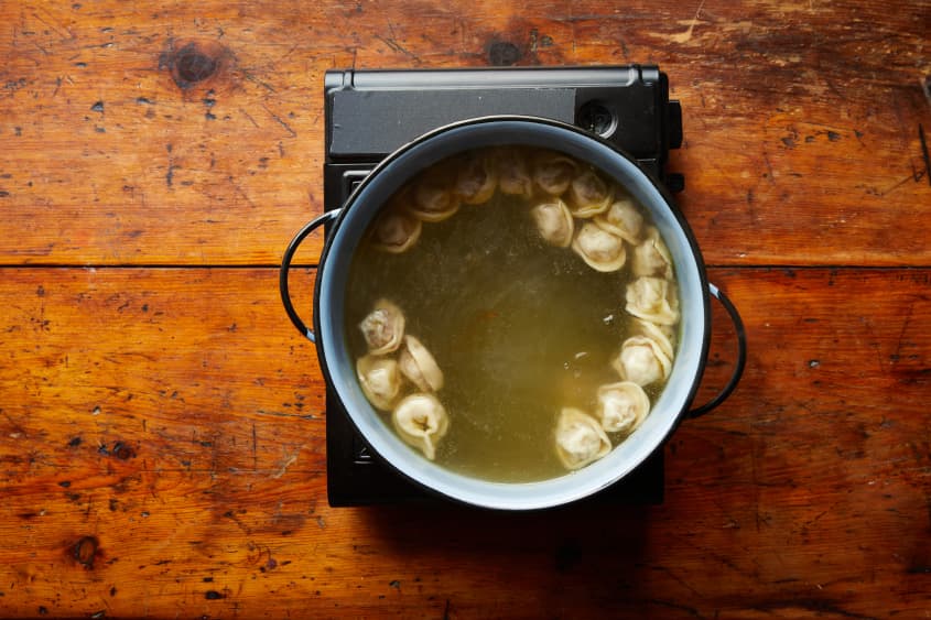 Pelmenis are boiled in a pot of water.