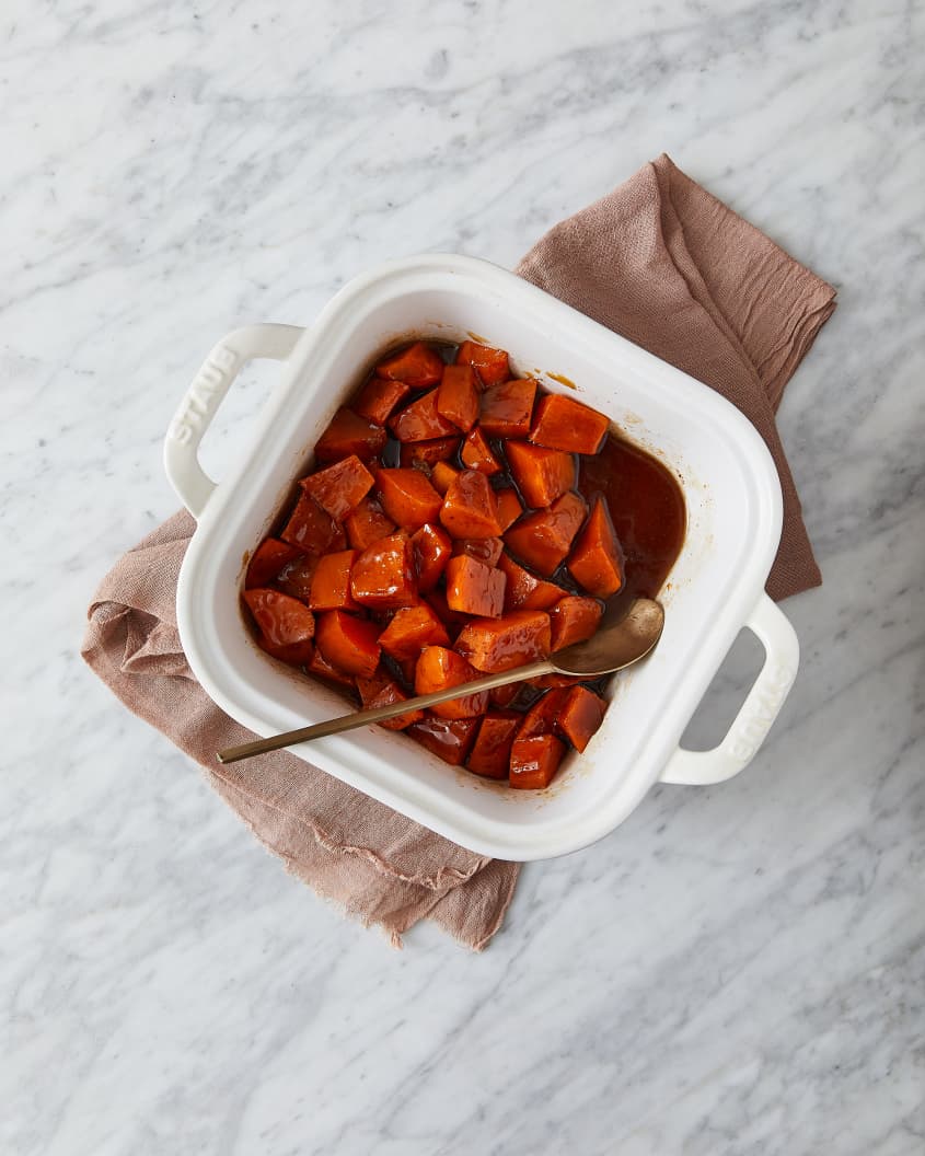 Southern candied yams in baking dish with serving spoon inside.