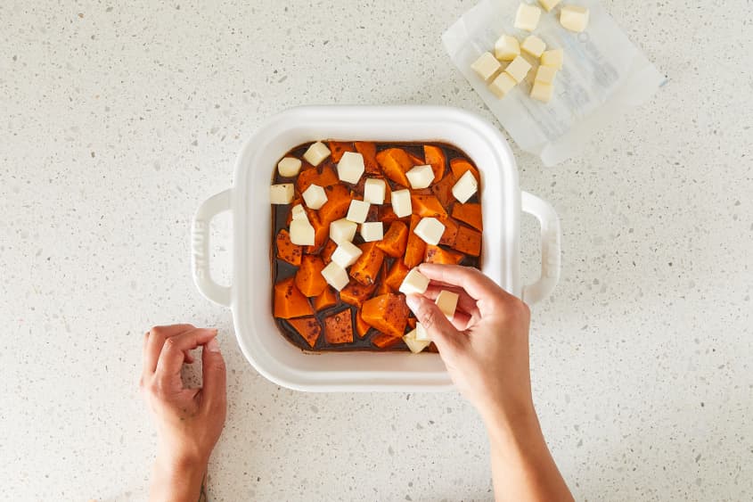 Cubes of butter added to candied yams in baking dish.