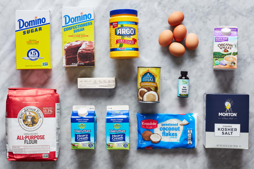 Coconut cream pie ingredients laid out; top row, left to right: granulated sugar, confectioners sugar, corn starch, eggs, half and half. Middle row; left to right: butter, coconut milk, vanilla extract. Bottom row; left to right: AP flour, heavy cream, coconut flakes, Kosher salt.