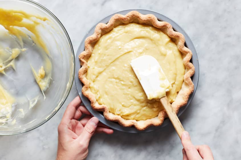 Coconut custard being spread onto pie crust.