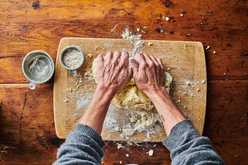 Hand kneading gnocchi dough on cutting board.