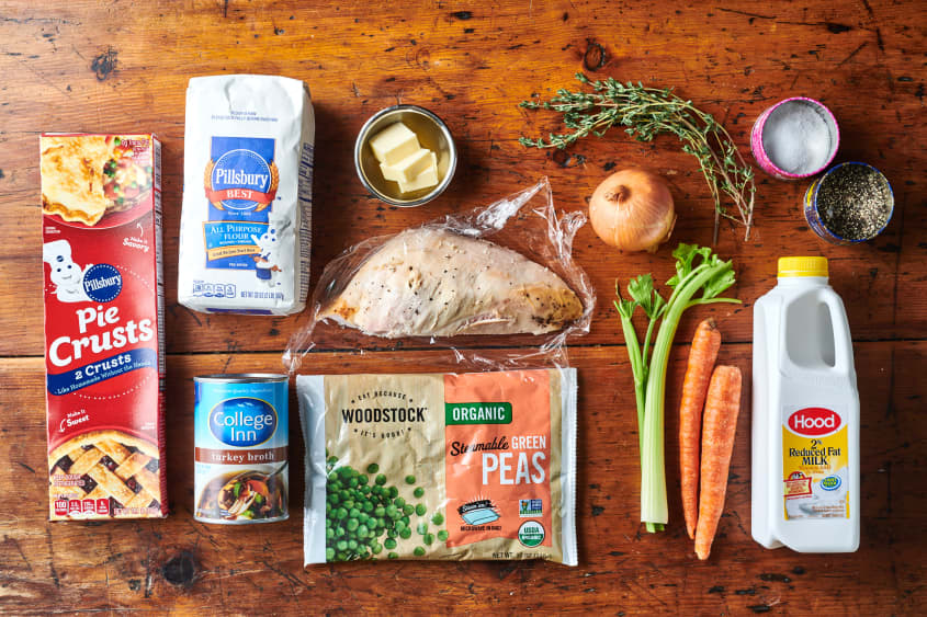 Ingredients for Leftover Turkey Potpie laid out; clockwise; salt and pepper, buttermilk, carrots, celery, peas, turkey stock, pie crust, flour, butter, onion, thyme.  Turkey breast in center.