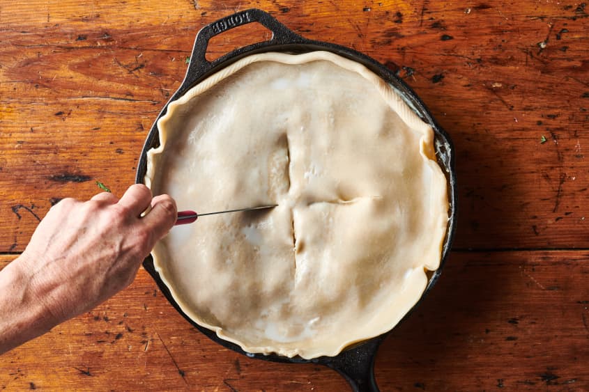 Someone slices steam holes into top of pie crust for turkey pot pie.