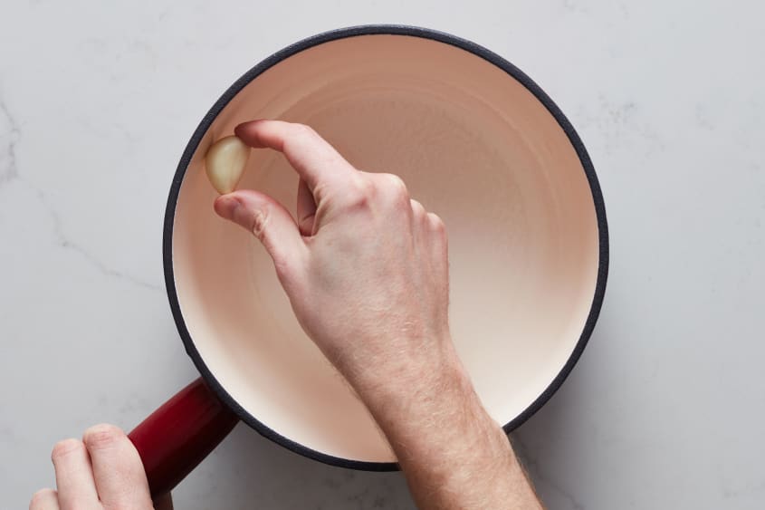 someone is rubbing garlic on the edges of an empty fondue pot