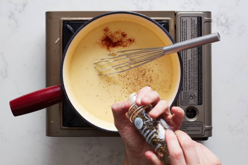 someone is mixing spices into a fondue pot on a burner