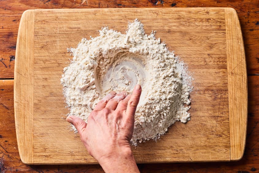 someone is making a hole in the middle of a mound of flour