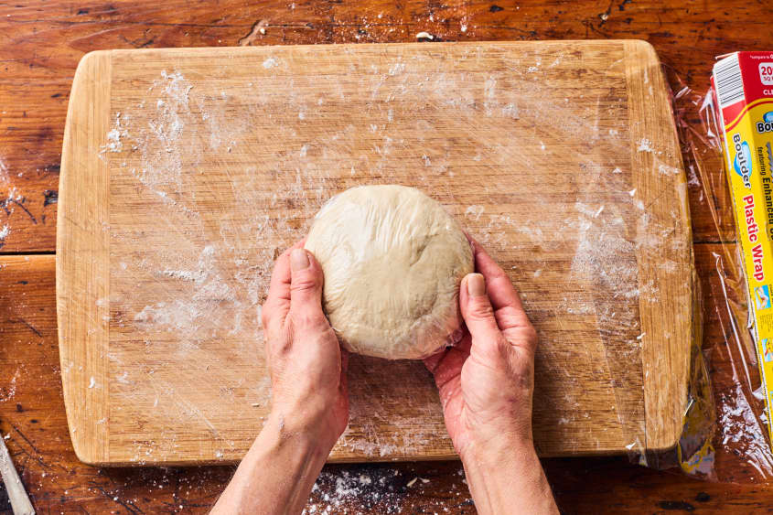 someone is holding the ball of dough over a cutting board