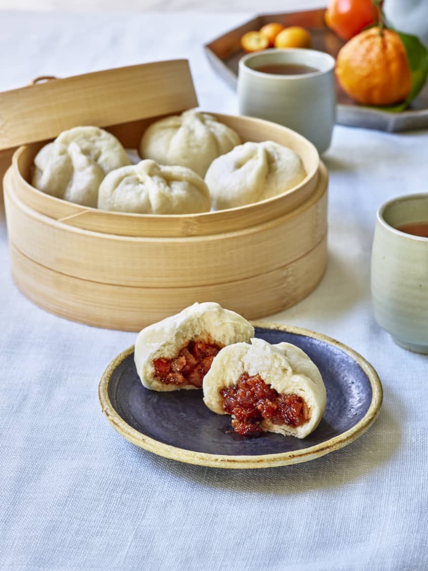bao buns sit on a plate and in a traditional container