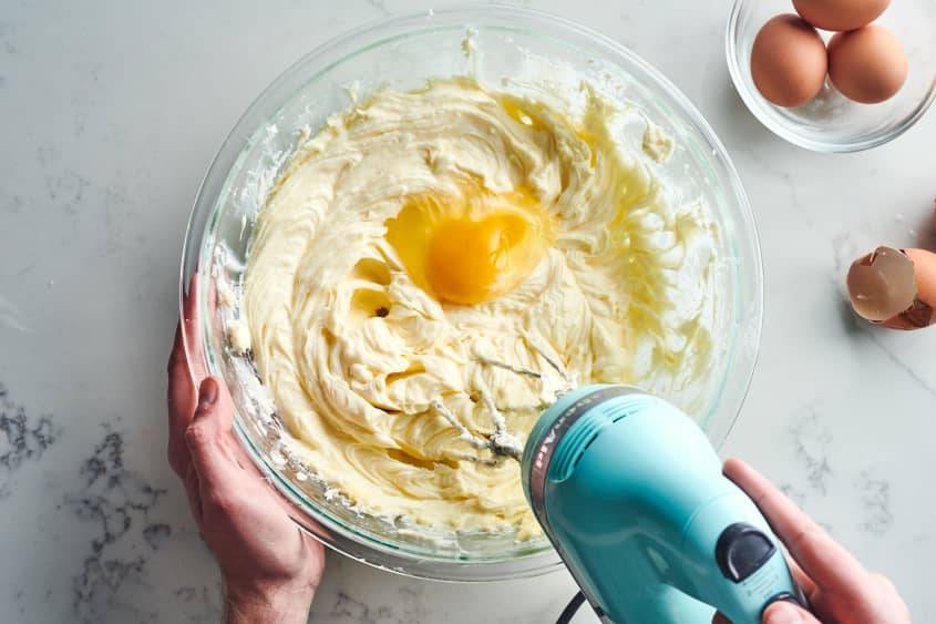 someone is using a mixer to mix egg into the batter