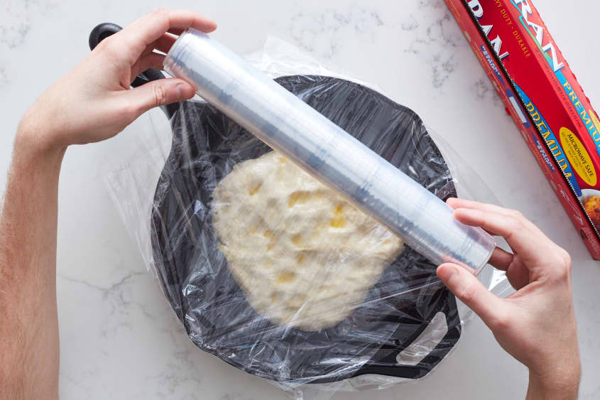someone is wrapping plastic wrap around the dough in a pan