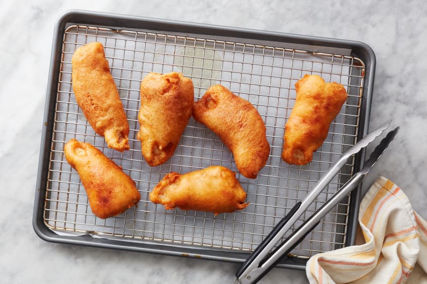 beer battered fish sits on a cooling rack on a sheet pan