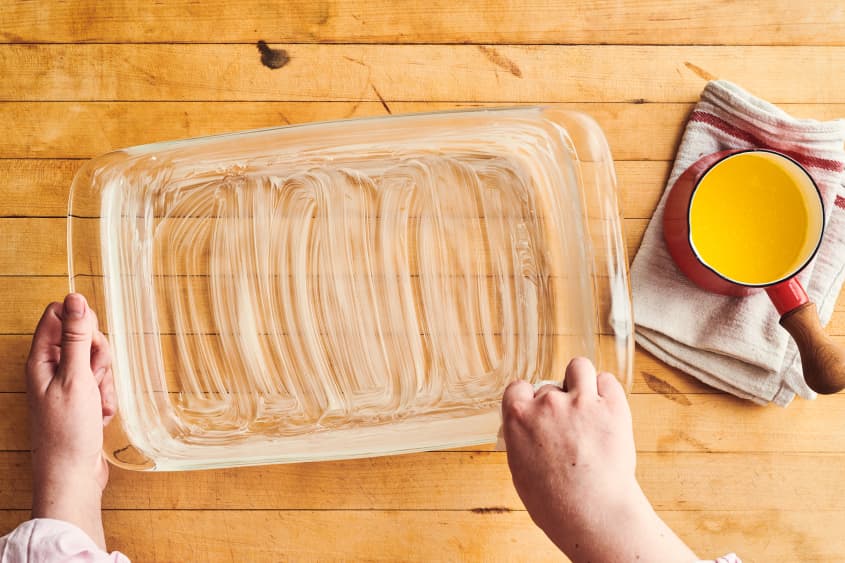 someone is lining a glass baking sheet with butter