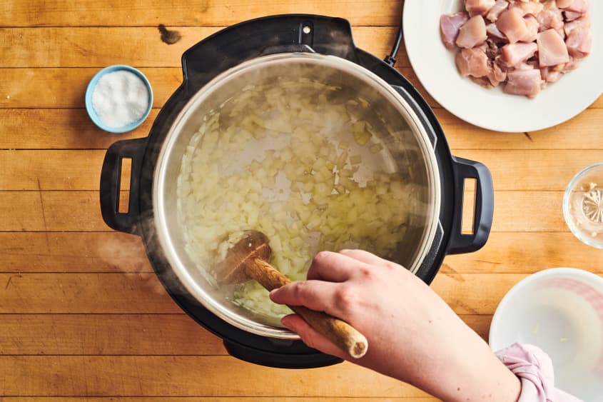 someone is stirring chicken and rice in instant pot