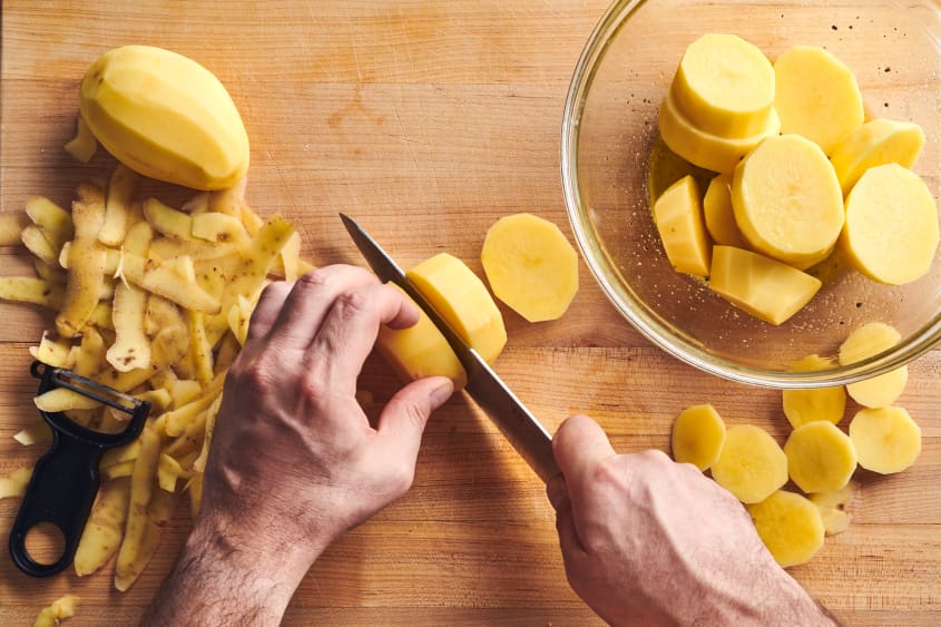 someone is slicing peeled potatoes
